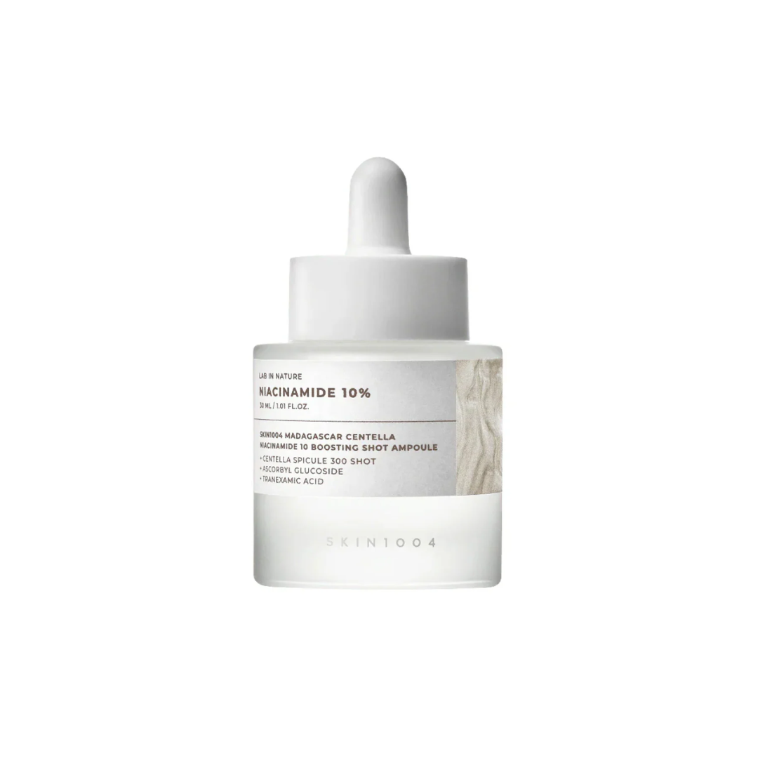 SKIN1004 Madagascar Centella Niacinamide 10 Boosting Shot Ampoule is a brightening serum that helps even out skin tone, reduce dark spots, and refine pores. It contains 10% Niacinamide along with Tranexamic Acid and Vitamin C to boost radiance and improve texture. The formula includes Hydrolyzed Sponge (Spicules) - microneedle-like natural structures that create tiny pathways in the skin to help active ingredients absorb better. Soothing ingredients like Centella Asiatica, Panthenol, and Madecassoside calm 